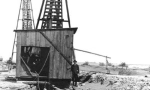 G-5925.1FF1-9 Workman standing to one side of pile driver on beach