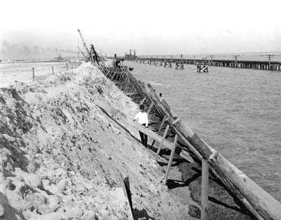 hotograph of workman holding wood bracing while standing on earth embankment