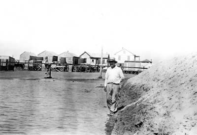 Grade Raising, Photograph of workman standing on embankment surrounding area being filled 