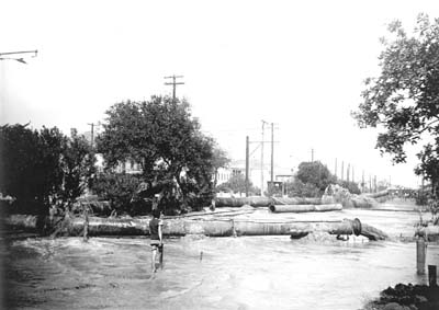 Grade Raising, Photograph of boy walking through fill being pumped into street