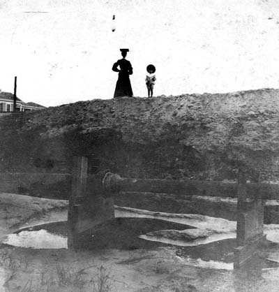 Grade Raising, Photograph of woman and girl standing on dike with pipeline below 
