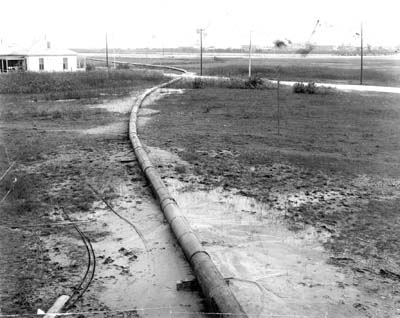 Grade Raising, Photograph of snaking pipeline carrying fill through marshy area
