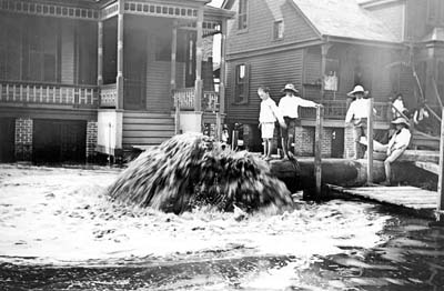 Photograph of children on pipeline watching it discharge fill 