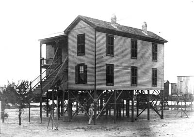 Photograph of two-story frame house raised for fill 