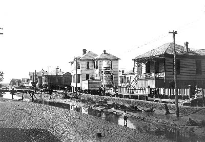 Photograph of boy walking along drainage ditch running next to residential area 