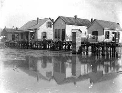 Photograph labeled The Picture illustrates how every dwelling in the City of Galveston...had to be raised by jacks 