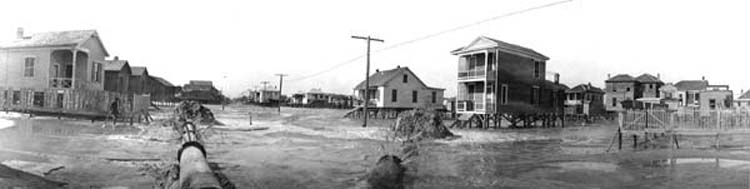 Photograph of panoramic view of fill being discharged around raised houses 