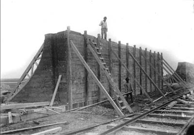 Photograph of worker standing atop section of Seawall under construction 