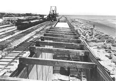 Photograph of steam mixer operating along railroad tracks behind wood caissons 