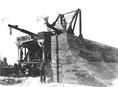 Photograph of workmen standing atop and next to completed section of Seawall 