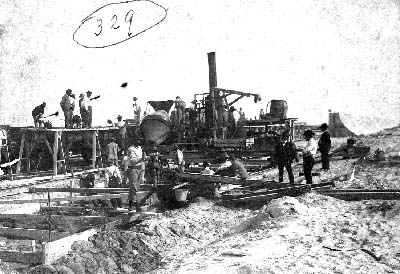 Photograph of workers pouring concrete into wood caissons 