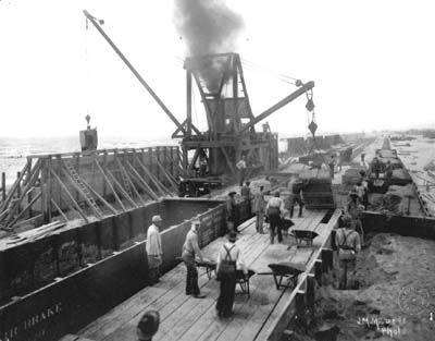Photograph of steam mixer pouring concrete in wood forms along Seawall 