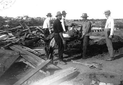 Photograph of workers carrying body amid debris