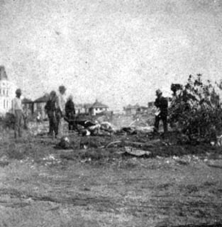 Photograph of workers placing bodies in pile