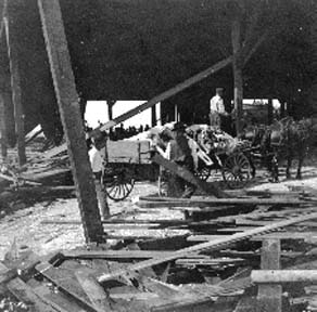 Photograph labeled On the wharf. Hauling the dead to be loaded onto barges.