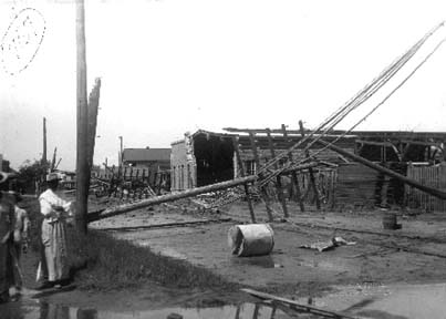 Photograph of fallen telephone poles and damaged commercial buildings