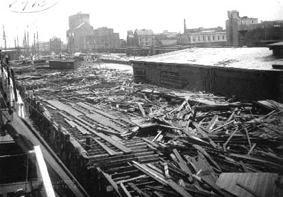 Photograph of debris and freight car strewn along wharf