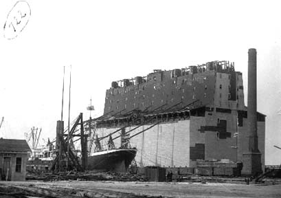 Photograph of steamship tied up next to wrecked grain elevator