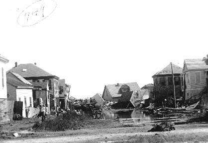 Photograph of standing water surrounded by wrecked houses