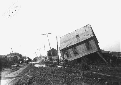 Photograph looking down street lined with wrecked houses