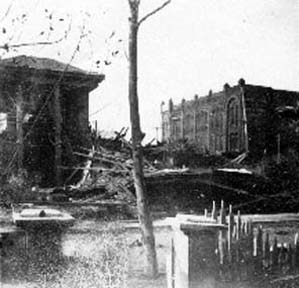 Photograph taken through gate toward buildings and debris