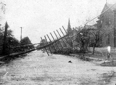 Photograph of utility poles fallen over into residential street