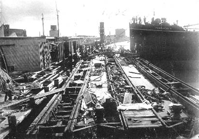 Photograph labeled Loading the barges with the dead