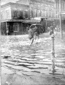 Photograph of people walking through flooded downtown street