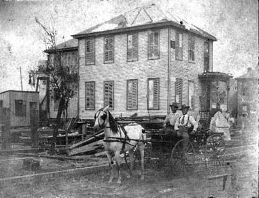 Photograph of two men seated in a horse and buggy in street