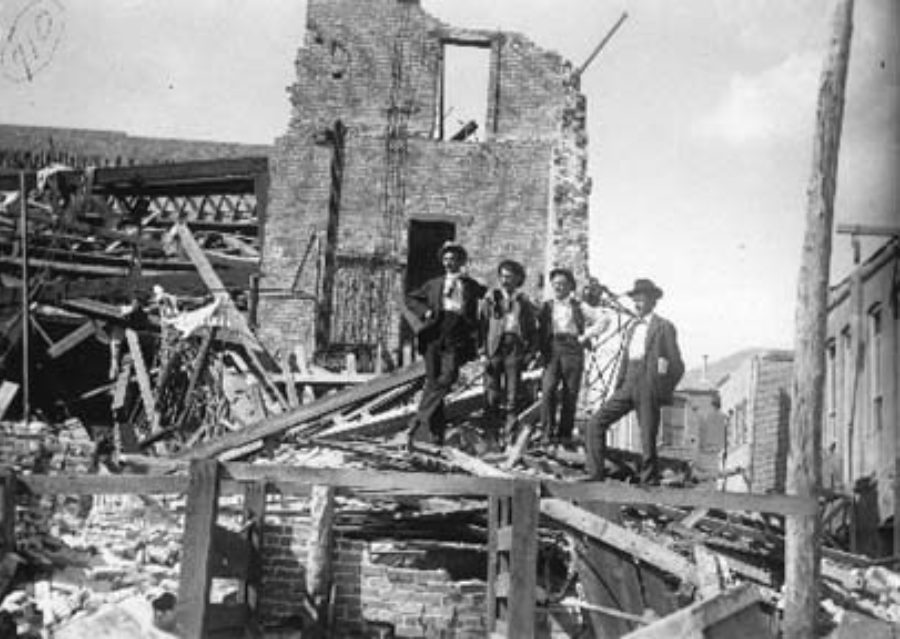 G-1771FF6.1-8 Four men posed standing on debris from Grand Opera House