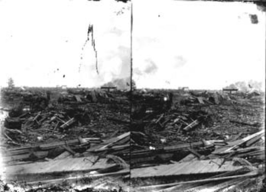 SC#194-42 Distant view of men with horse and buggy amid debris.