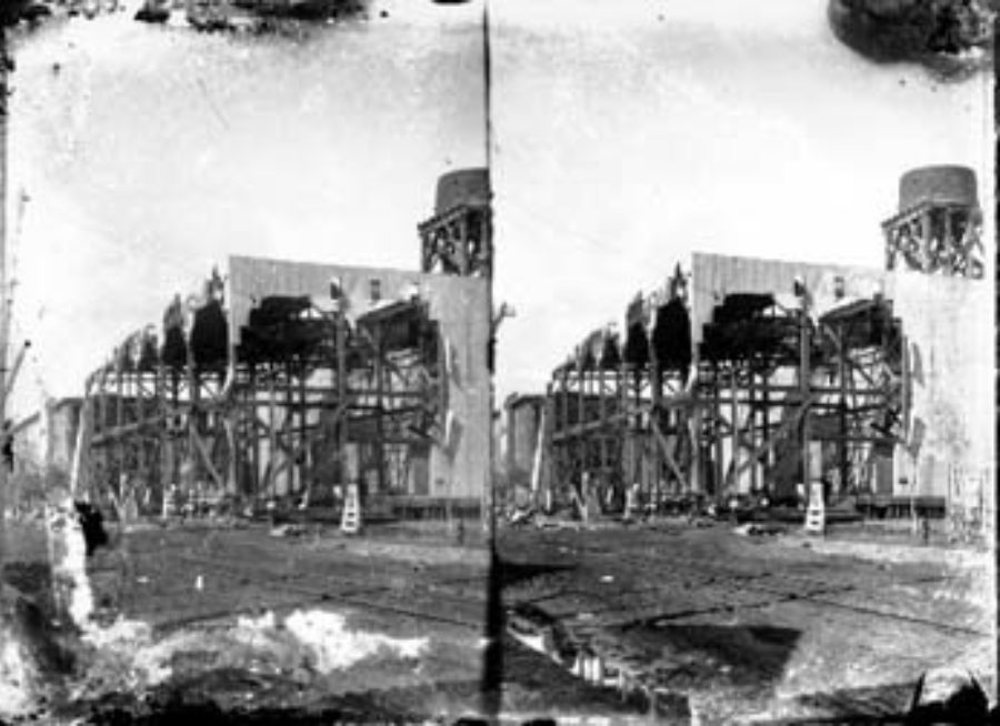 SC#194-9 Two-story damaged building, possibly warehouse, with cistern on its roof.